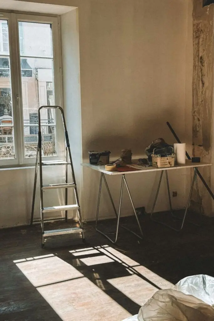 Pièce en travaux avec escabeau, outils, peinture et bâches de protection