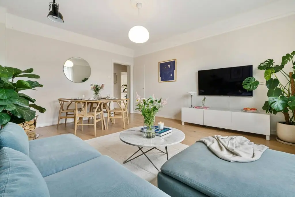 Salon épuré et végétalisé avec canapé bleu et mobilier bois blanc