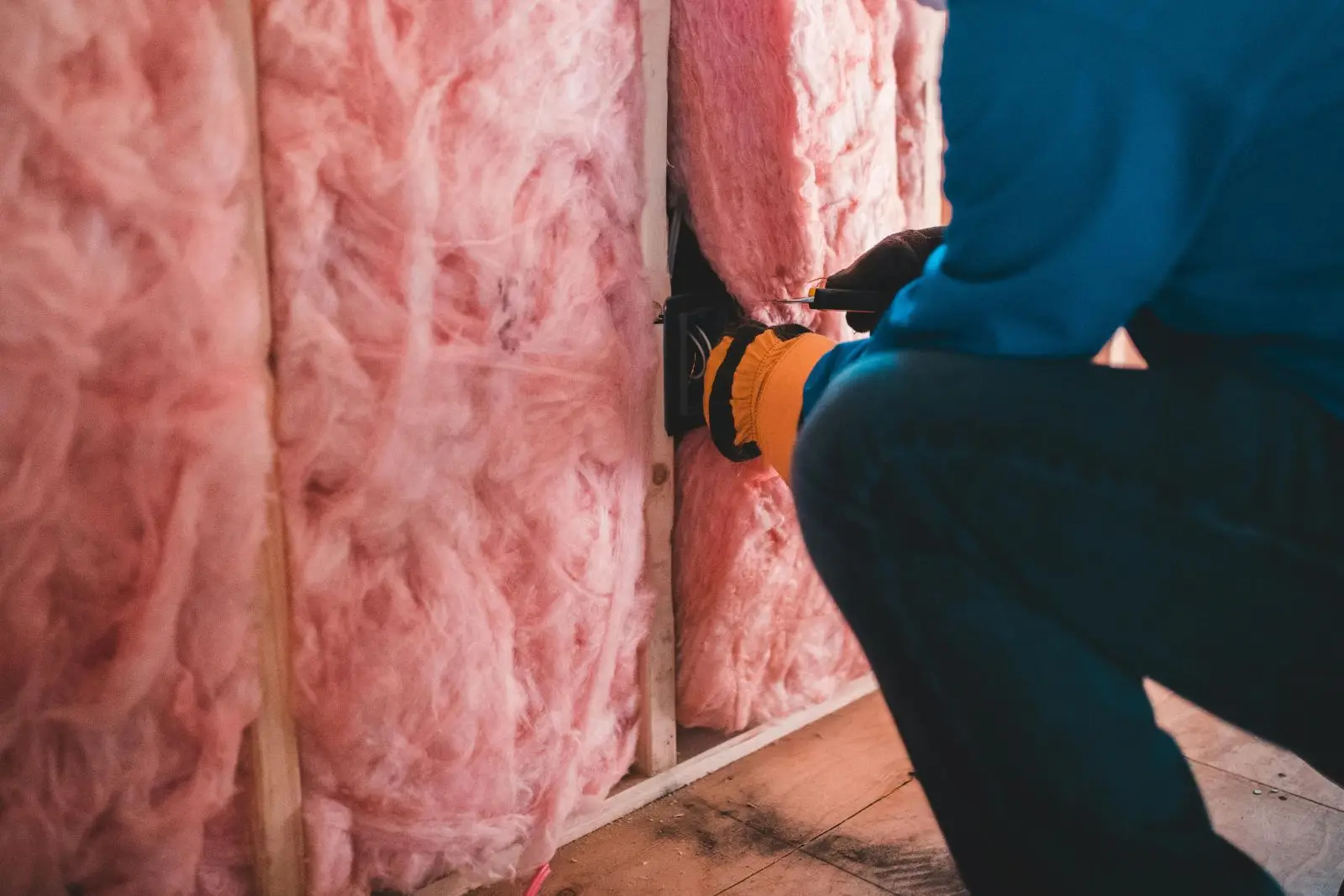 Artisan posant un isolant thermique entre des cloisons dans une maison en rénovation