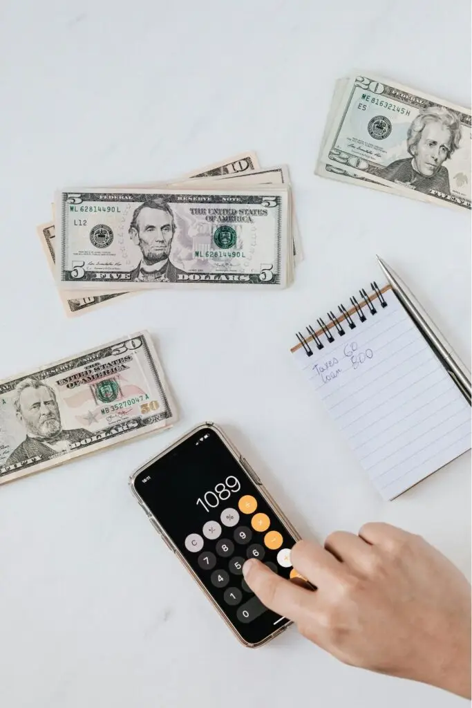 Calculatrice, argent liquide et carnet de budget pour estimer les aides à la rénovation