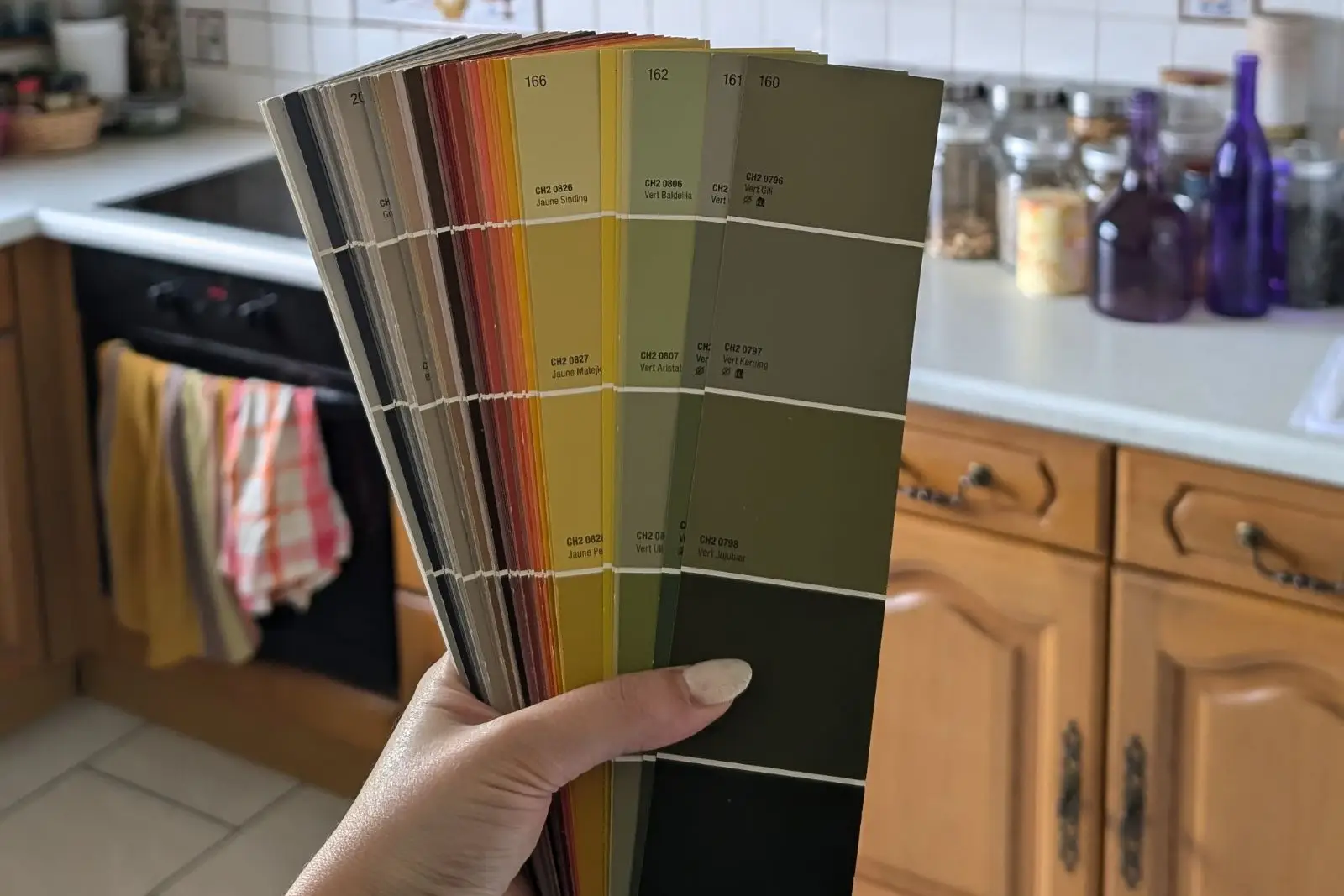 Main d’Alice Vadurel tenant un nuancier de peinture dans la cuisine d’un projet client