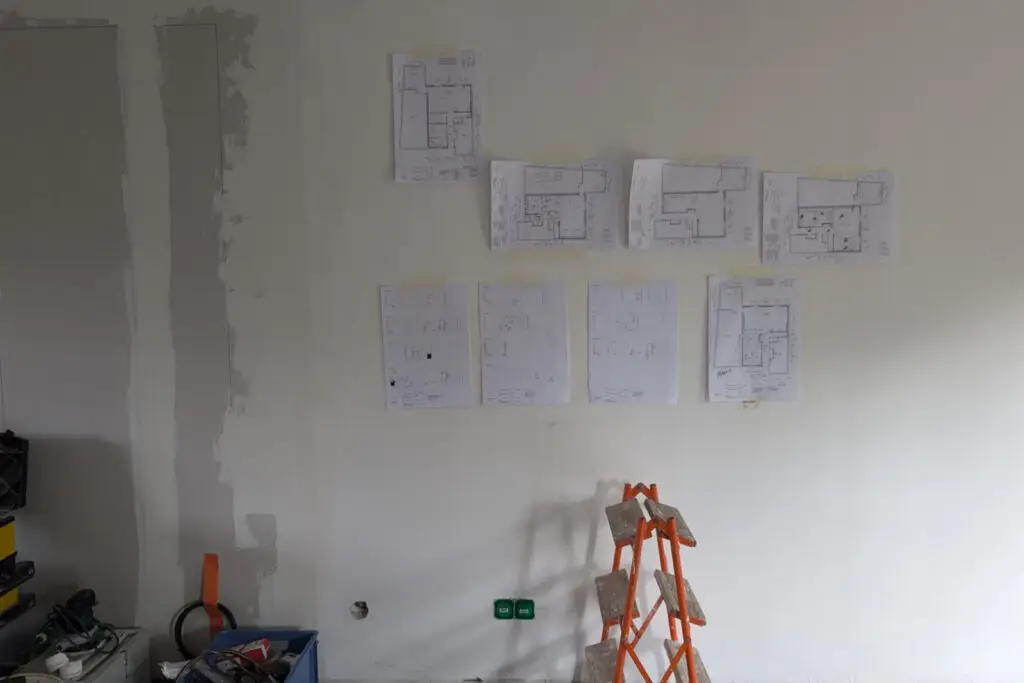 Photo de chantier avec plans affichés sur le mur pour suivi du projet
