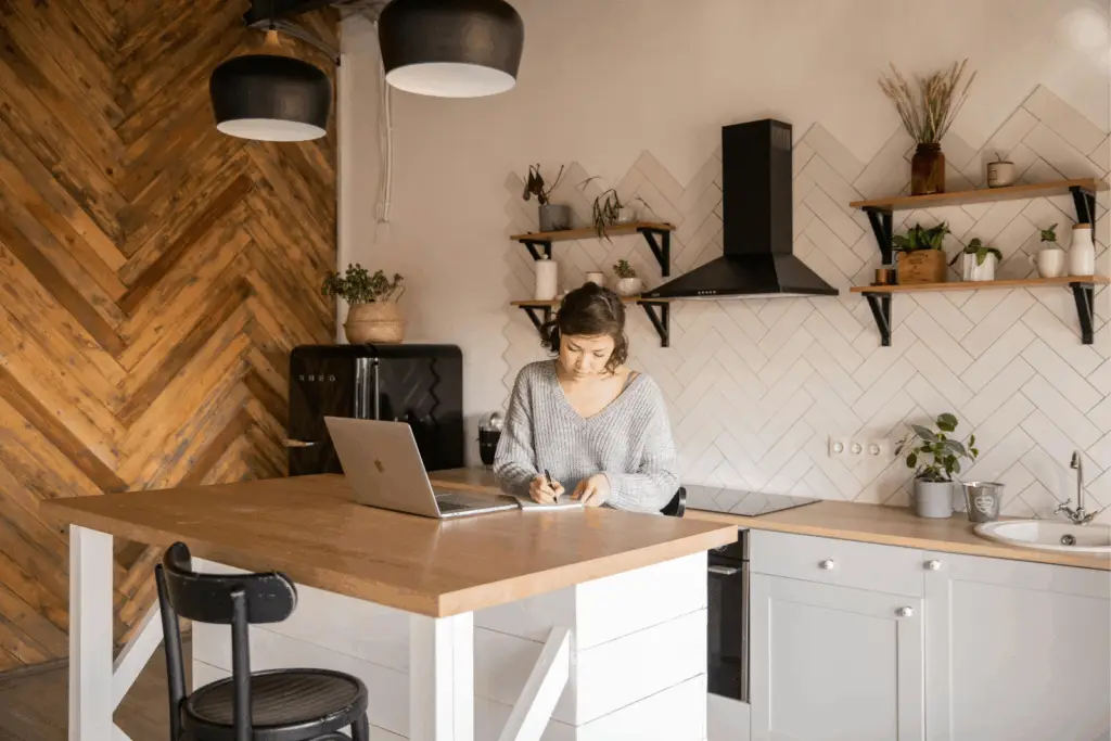 Femme travaillant sur un carnet dans une cuisine rénovée avec îlot central