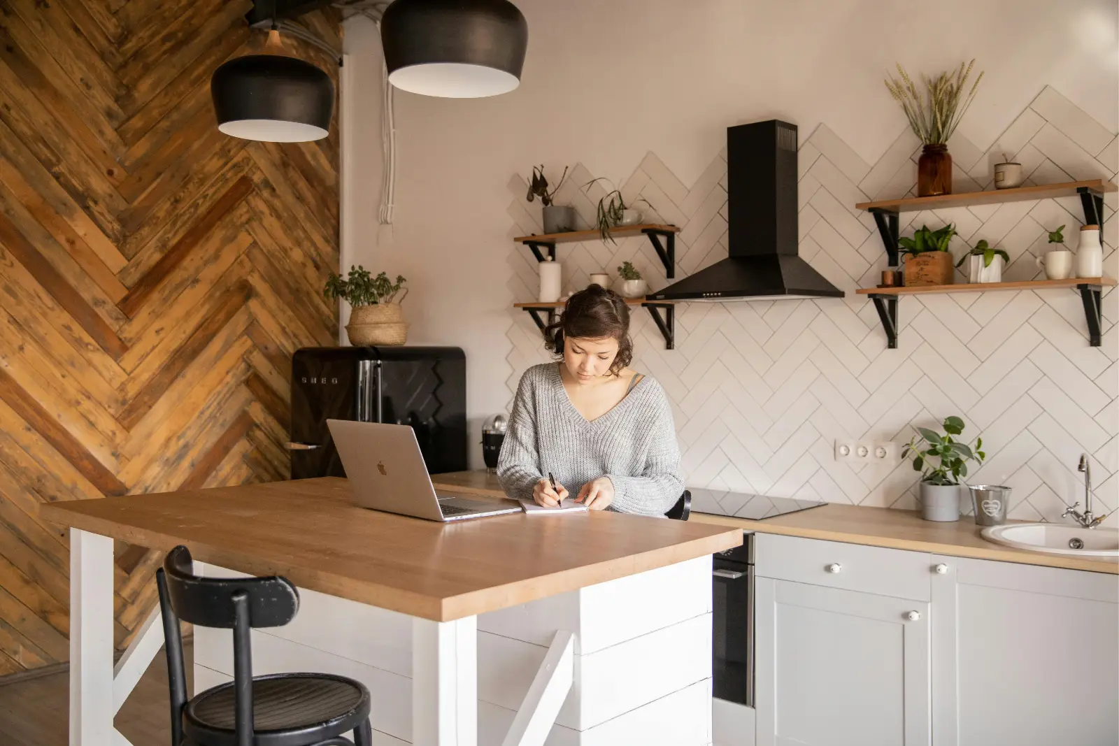 Femme travaillant sur un carnet dans une cuisine rénovée avec îlot central