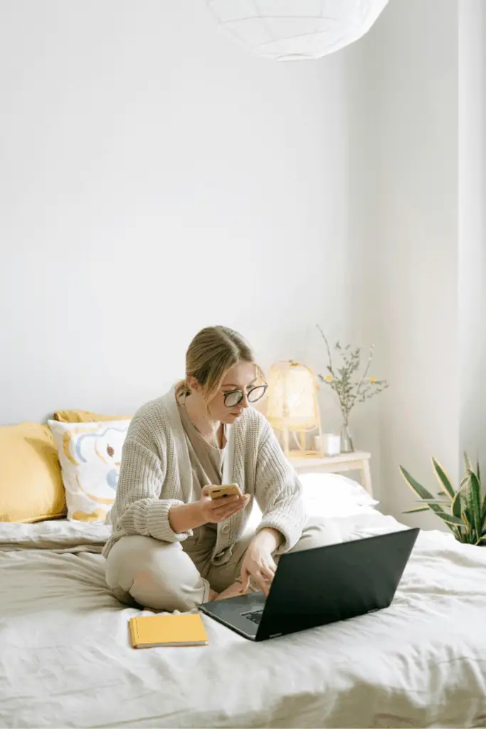 Jeune femme en pyjama travaillant sur son lit avec un ordinateur portable