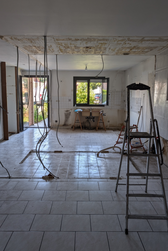 Chantier de rénovation en phase de démolition avec cloisons retirées et câbles apparents